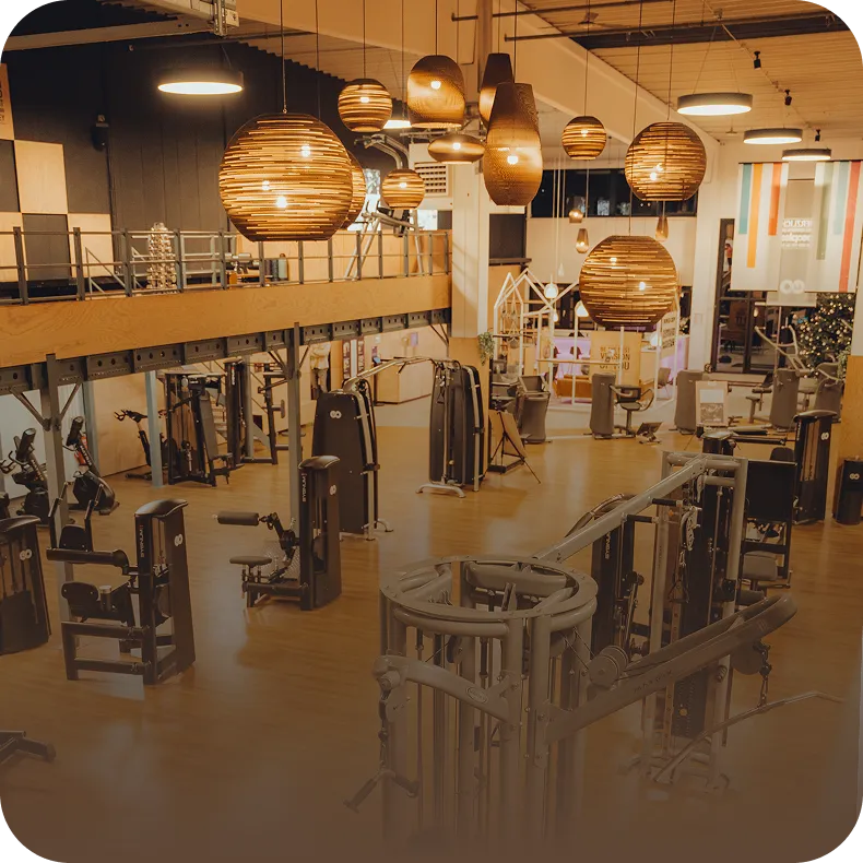 Weitläufige Trainingsfläche mit modernen Kraftgeräten und Design-Hängeleuchten im Peoples Fitness Studio